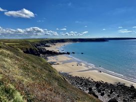 A beach with rocks and water under a blue sky at Tower Cottage near Pembroke