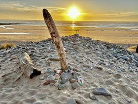 A beach with stones and driftwood at sunset at Tower Cottage Near Pembroke