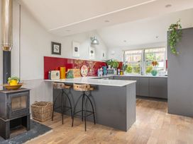 A kitchen with a stove, sink, microwave, and bar stools at 14 Marine Parade in Lyme Regis
