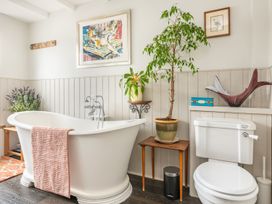A bathroom with a bathtub, toilet, and plant at 14 Marine Parade in Lyme Regis