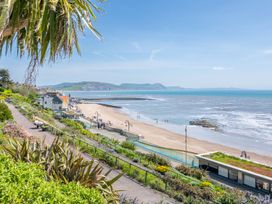 A beach with a pathway and plants along the shoreline at 14 Marine Parade in Lyme Regis