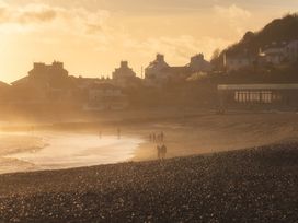 A beach with people walking and houses in the background at 14 Marine Parade Lyme Regis