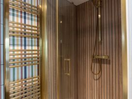 A shower with a gold shower head and heating ladder at Port House in Lyme Regis