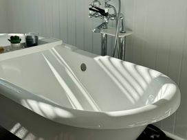 A bathtub with a faucet and a tray holding a plant at Port House in Lyme Regis