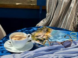 A coffee cup and magazine on a table in an outdoor seating area at Port House Lyme Regis