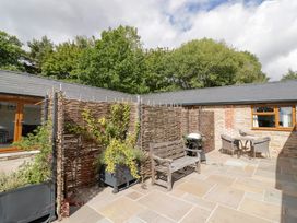 An outdoor area with a patio, bench, and dining table at Keepers Barn Bromyard