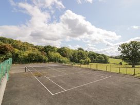 A tennis court with a fence and trees at Keepers Barn in Bromyard