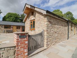 An exterior view of a stone building with a wooden gate and paved pathway at Keepers Barn in Bromyard