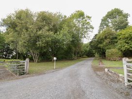 A gravel road with trees and a gate at Keepers Barn in Bromyard