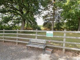 An outdoor smoking area with a bench and trees at The Cow Shed in Bromyard