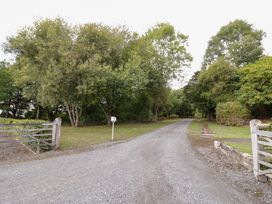 A gravel road lined with trees and a gate at The Cow Shed in Bromyard