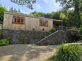A wooden cabin with windows and a stone wall at Ty Barddu in Cwmorgan near Newcastle Emlyn