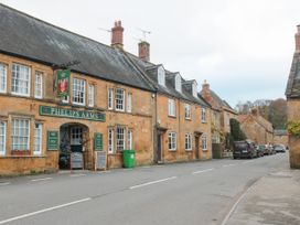 A street view with stone buildings and a pub named Phelips Arms in Montacute