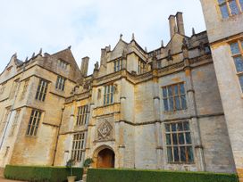 An old stone building with multiple windows and architectural details with bushes in front at Two Towers Cottage in Montacute