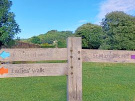 A wooden signpost with directions for Parkland walk Ladies walk and St Michaels Hill in a grassy area with trees