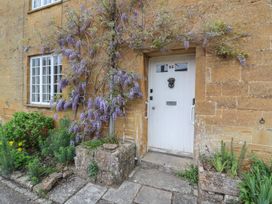 A white door with the number 23 and flowering plants growing on a stone wall at Two Towers Cottage in Montacute