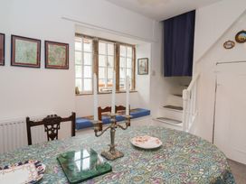 A dining area with a table covered in a patterned tablecloth and three white candles on a candelabra at Two Towers Cottage Montacute