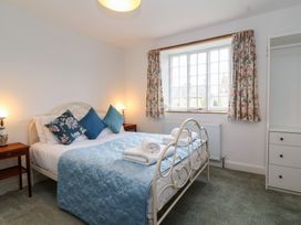 A bedroom with a bed with blue bedspread and pillows beside two wooden bedside tables with lamps at Two Towers Cottage Montacute