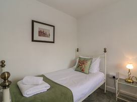 A single bed with white sheets and green blanket with folded white towels on a bed in a bedroom at Two Towers Cottage in Montacute
