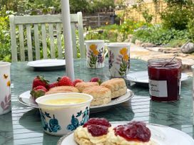 An outdoor dining table with scones, strawberries, and jam at Two Towers Cottage in Montacute