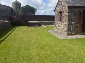 A garden with grass and a hot tub at Yr Hen Stabl Llanwnda near Bontnewydd, Gwynedd