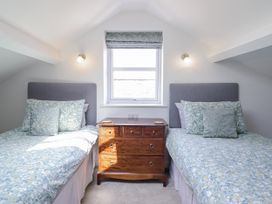 A bedroom with two beds and a wooden chest of drawers at Neptune Cottage in Conwy