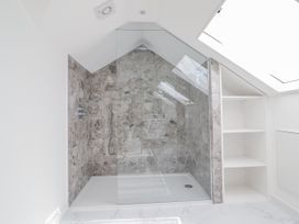 A shower with tiled walls and shelves at Neptune Cottage Conwy