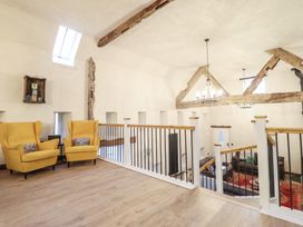 A living room area with yellow chairs and wood beams at Godre'r Gyrn, Plas Moelfre Hall Barns Oswestry
