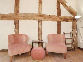A living room with two chairs, a table, a lamp, and a stool at Godre'r Gyrn, Plas Moelfre Hall Barns, Oswestry