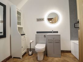 A bathroom with a toilet, sink, mirror, cabinet, and a sign at Godre'r Gyrn, Plas Moelfre Hall Barns Oswestry