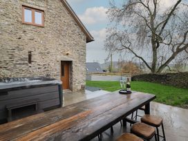 An outdoor area with a hot tub and dining table at Godre'r Gyrn, Plas Moelfre Hall Barns, Oswestry