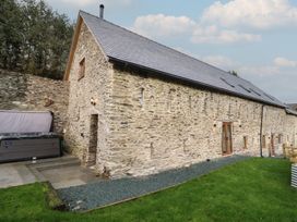 An outdoor view of a stone building with windows and hot tub at Godre'r Gyrn, Plas Moelfre Hall Barns, Oswestry