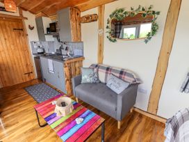 A small living area with a gray sofa, colorful coffee table, and kitchenette with gray cabinets and wooden accents at Moel Y Parc in Bryniau Clwyd near Denbigh