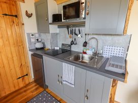A kitchen with grey cabinets a sink a microwave and utensils at Moel Y Parc in Bryniau Clwyd near Denbigh