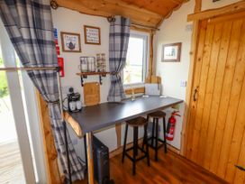 A small dining area with a counter table and two stools near a wooden door and window at Moel Y Parc in Bryniau Clwyd near Denbigh