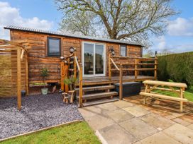 A wooden cabin with a small deck and stairs surrounded by a garden and a picnic table at Moel Y Parc in Bryniau Clwyd near Denbigh
