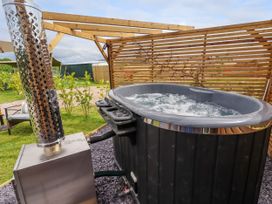 An outdoor hot tub with bubbling water next to a metal heater and wooden privacy screens at Moel Y Parc in Bryniau Clwyd near Denbigh