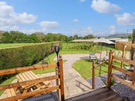 An outdoor garden area with wooden picnic table umbrella chairs and a patio at Moel Y Parc in Bryniau Clwyd near Denbigh