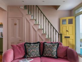 A living room with a pink sofa and yellow door at Astondene, East Cliff in Southwold