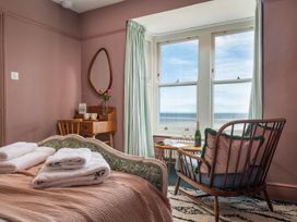 A bedroom with a view of the sea and a chair at Astondene, East Cliff Southwold