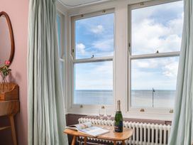 A window view with a table holding champagne and a magazine at Astondene, East Cliff Southwold