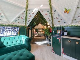 A living room with a sofa and kitchen area at Applejacks Orchard in Holywell