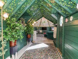 A room with plants, a sofa, television, and chairs at Applejacks Orchard Holywell