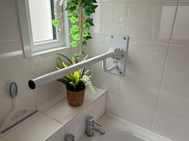 A bathroom with a grab bar and a plant at Waves End in Mevagissey