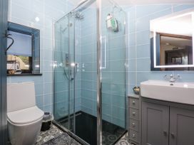 A bathroom with a toilet, shower, sink, and mirror at Windyridge, Gwaenysgor, near Prestatyn