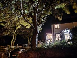 A house with a lit window and a car parked at Windyridge, near Prestatyn