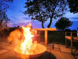 An outdoor seating area with a fire pit and table at Windyridge, Gwaenysgor, near Prestatyn