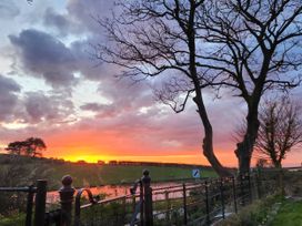 A sunset view with trees and a fence at Windyridge in Gwaenysgor, near Prestatyn