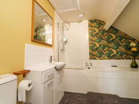 A bathroom with a sink, toilet, mirror, and shower at Mallards Rest Llandwrog near Bontnewydd, Gwynedd