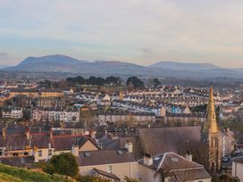 A view of houses and a church with mountains in the background at Mallards Rest in Llandwrog near Bontnewydd, Gwynedd